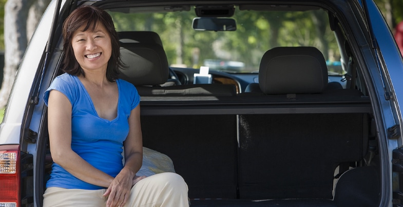 Oriental women sitting in the back of SUV on a summer day