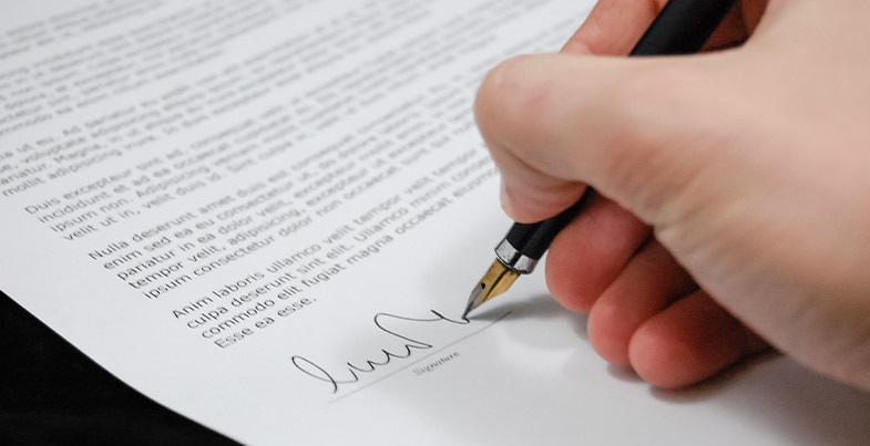  A man's hand with a pen signing the auto consignment agreement