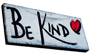Be kind to others sign with red heart painted on it