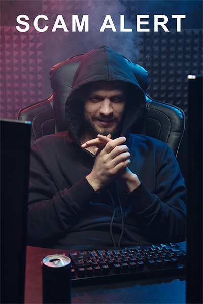 man with hoodie and looking evil behind dual monitors
